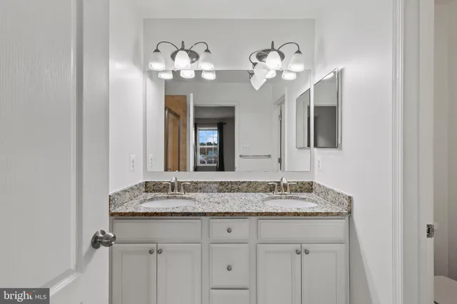 a bathroom with a granite countertop sink a large mirror and cabinets