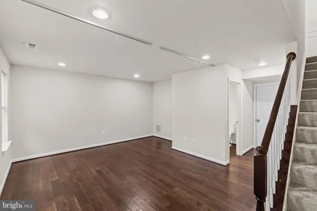 a view of an empty room with wooden floor and stairs