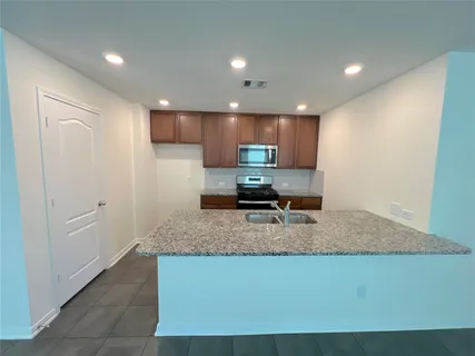 a kitchen with stainless steel appliances granite countertop a sink a stove and a refrigerator