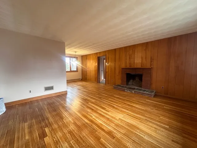 an empty room with wooden floor and a fireplace