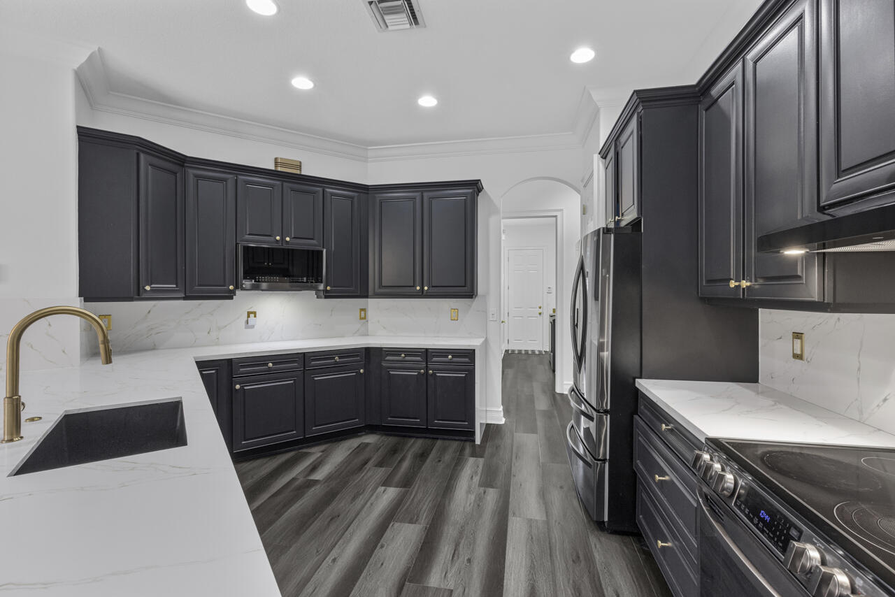 8300 Southwest Cattleya Drive Stuart, FL 34997 - Photo 27 of 77 a kitchen with stainless steel appliances granite countertop a refrigerator a stove top oven a sink and dishwasher