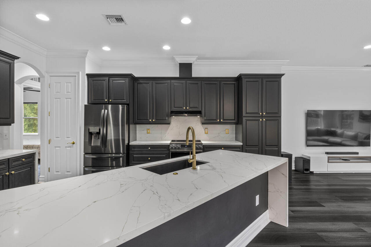 8300 Southwest Cattleya Drive Stuart, FL 34997 - Photo 37 of 77 a kitchen with kitchen island a sink appliances and cabinets
