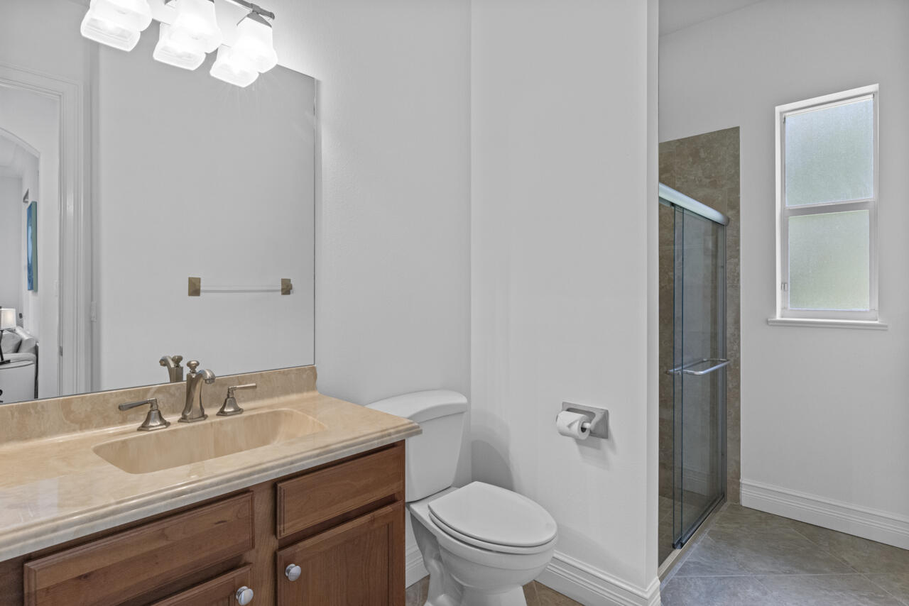 8300 Southwest Cattleya Drive Stuart, FL 34997 - Photo 46 of 77 a bathroom with a toilet a sink a mirror and vanity