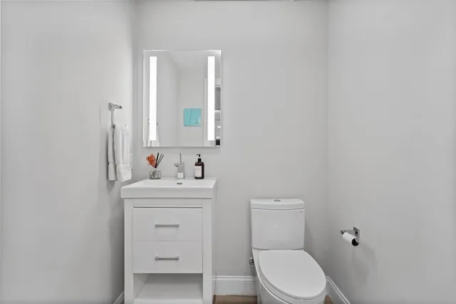a bathroom with a toilet a sink a vanity and mirror