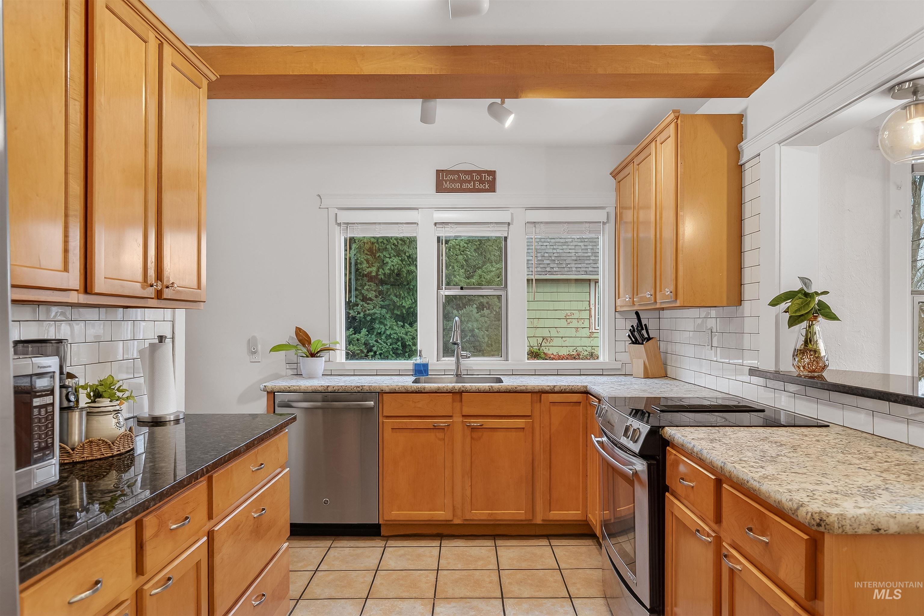 1209 3rd Street Lewiston, ID 83501 - Photo 11 of 49 Kitchen with tasteful backsplash, appliances with stainless steel finishes, dark stone counters, light tile patterned floors, and beam ceiling
