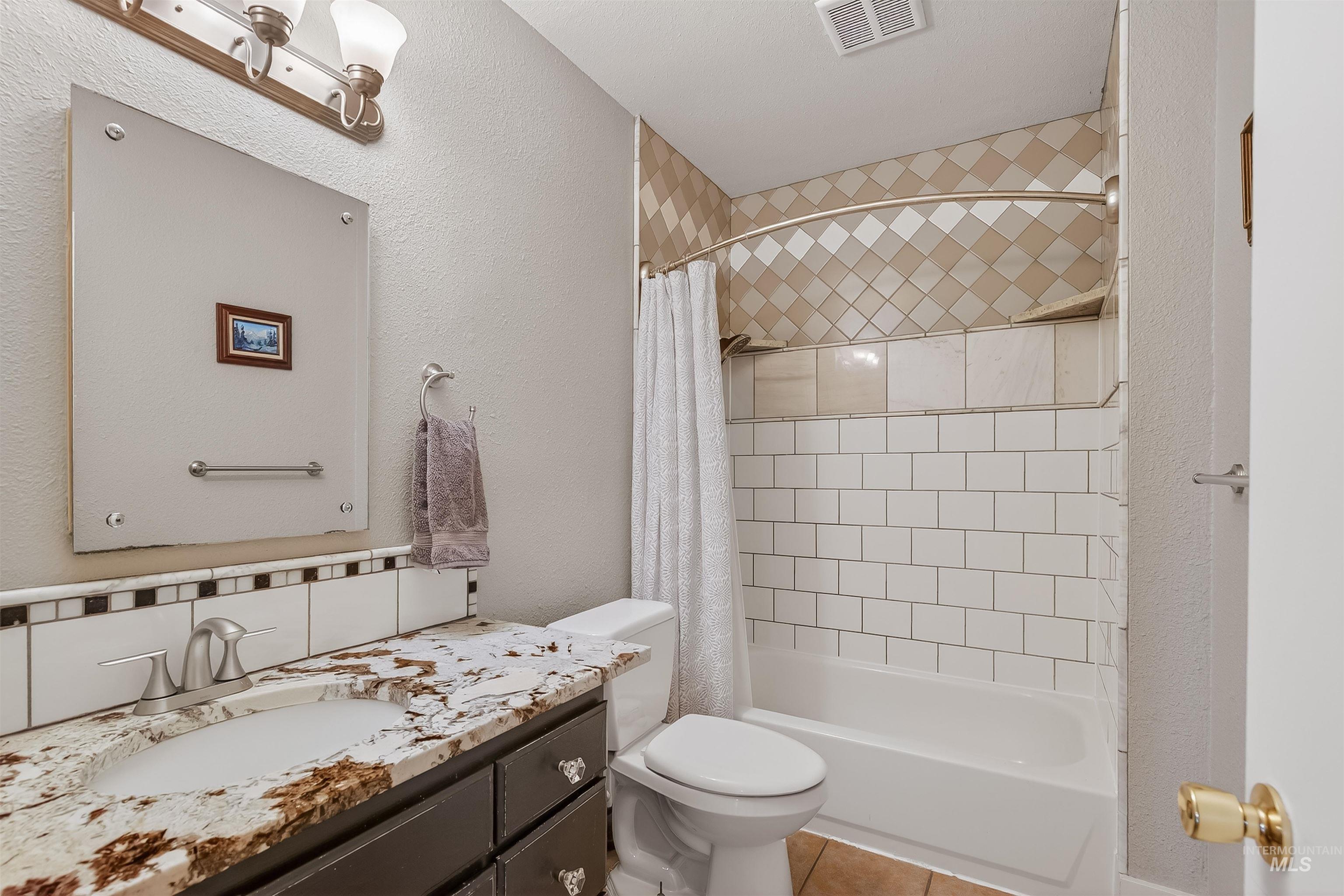 1209 3rd Street Lewiston, ID 83501 - Photo 26 of 49 Bathroom with a textured wall, shower / bath combo with shower curtain, vanity, and light tile patterned floors
