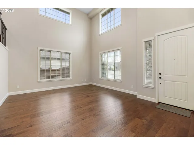 an empty room with wooden floor cabinet and windows