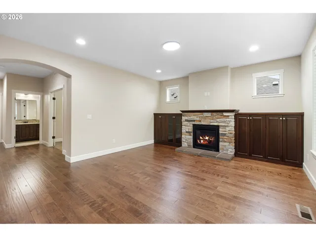 a view of an empty room with wooden floor and a fireplace