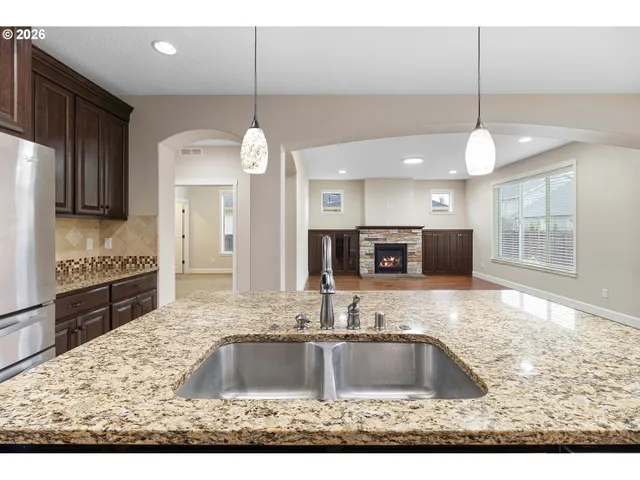 a kitchen with kitchen island granite countertop a sink a counter top space cabinets and stainless steel appliances