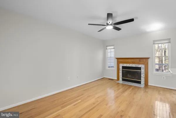 a view of empty room with wooden floor fireplace and a window