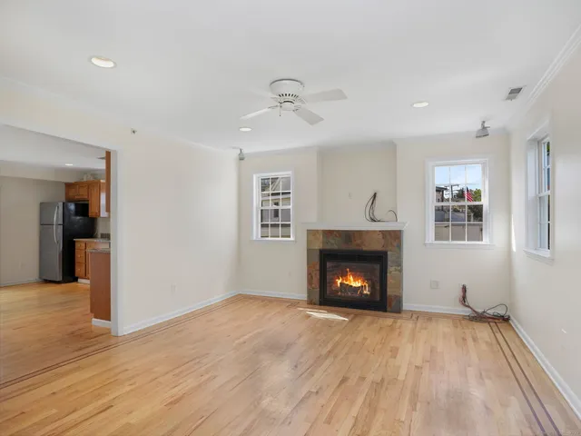a view of an empty room with wooden floor fireplace and a window