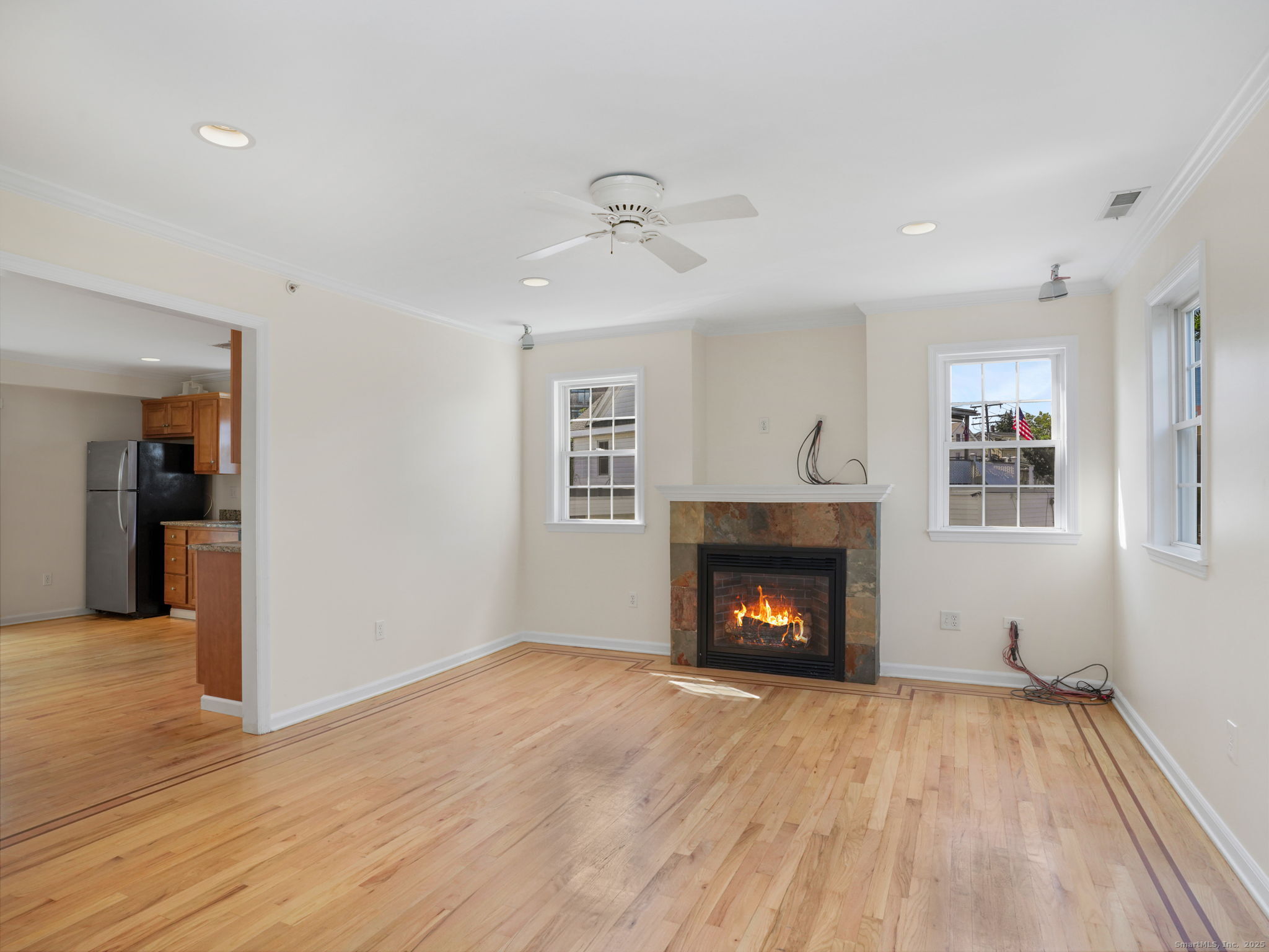 a view of an empty room with wooden floor fireplace and a window