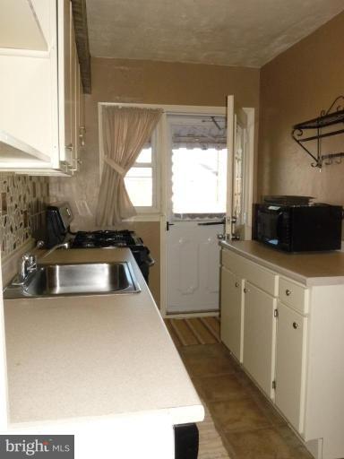 444 Stemmers Run Road Essex, MD 21221 - Photo 7 of 30 a kitchen with a sink a window a counter top space and stainless steel appliances