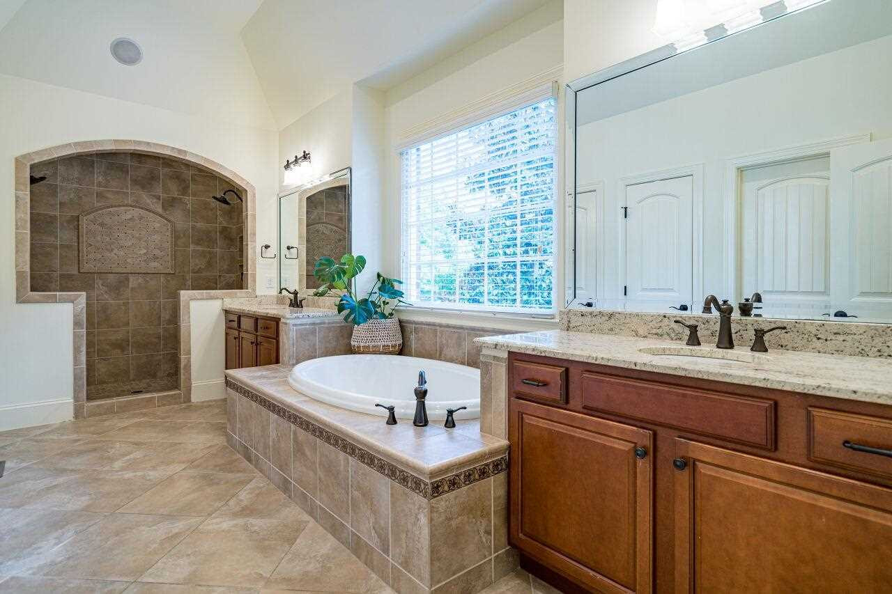3820 Laurel Hills Road Raleigh, NC 27612 - Photo 16 of 30 Lovely tile surrounds this spa retreat on the main level. Walk in shower, garden tub, separate vanities, water closet, two walk in closets make this bathroom a stunning feature of this home! Owner's Bath