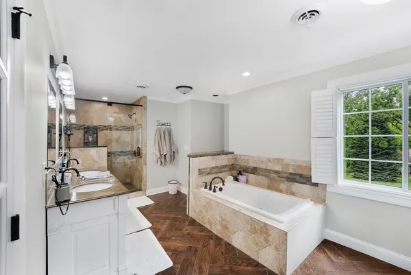 a spacious bathroom with a tub sink and mirror