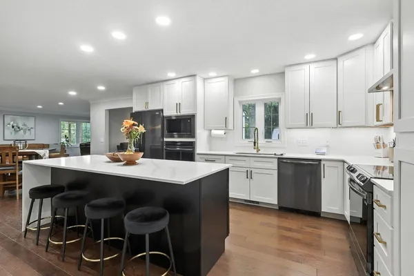 a kitchen with a sink a stove a refrigerator and white cabinets with wooden floor
