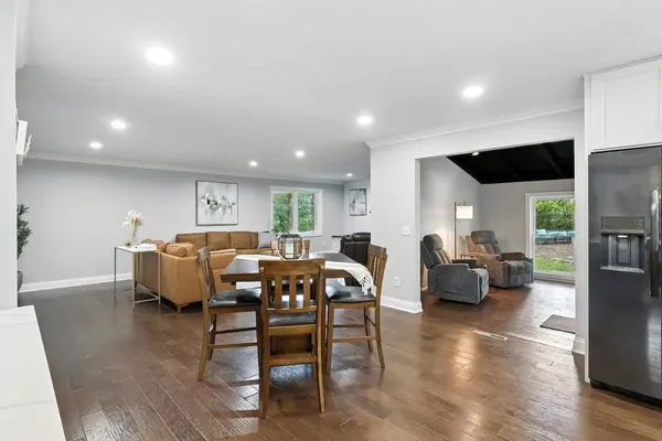 a living room with furniture two large window and wooden floor