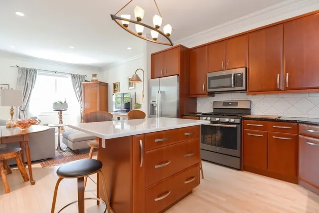 a kitchen with stainless steel appliances granite countertop a stove top oven a sink dishwasher a dining table and chairs with wooden floor