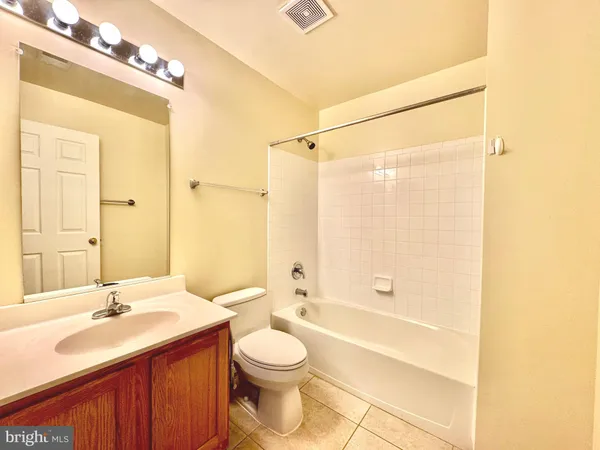 a bathroom with a bathtub shower sink vanity mirror and toilet
