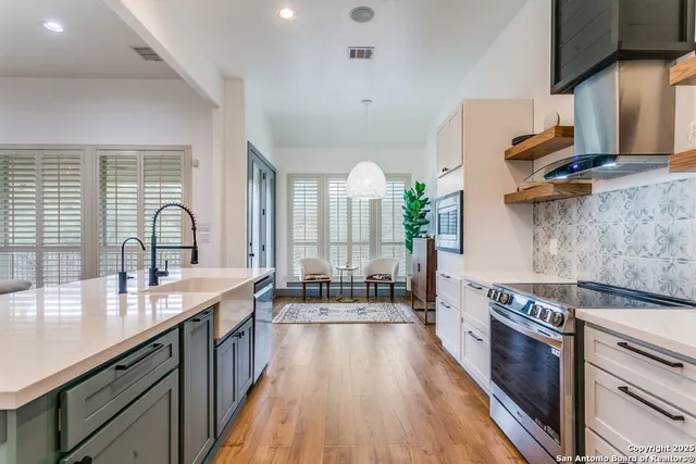 a large kitchen with granite countertop a stove a sink dishwasher and a microwave oven with white cabinets