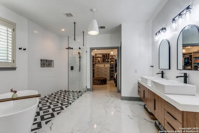 a spacious bathroom with a double vanity sink a large mirror and shower