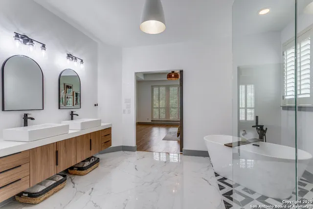 a spacious bathroom with a double vanity sink mirror and bathtub