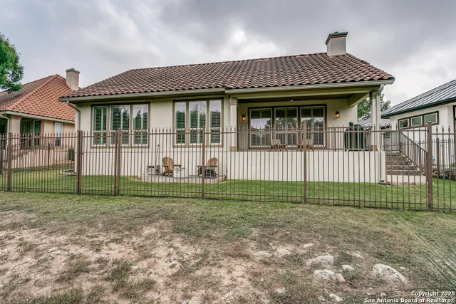 a view of a house with a small yard and a large tree front of it