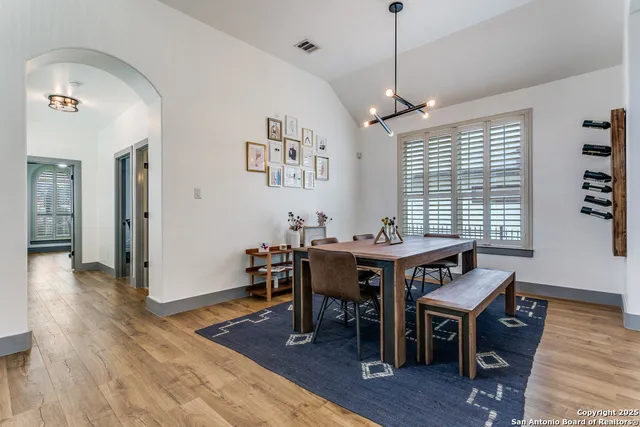 a dining room with wooden floor a chandelier a wooden table and chairs