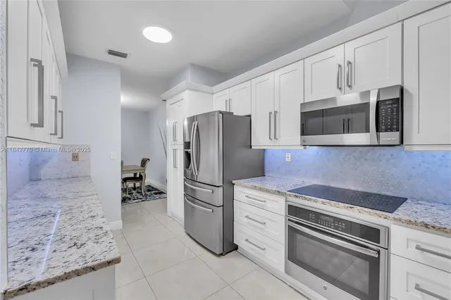a kitchen with granite countertop a refrigerator stove and microwave