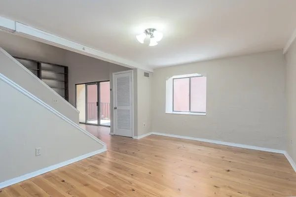 a view of empty room with wooden floor and fan