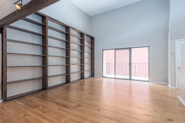 a view of an empty room with a window and wooden floor