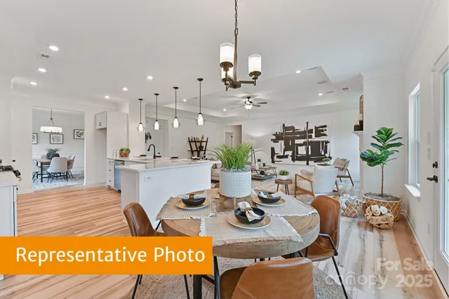 a view of a dining room and livingroom with furniture wooden floor a rug a painting and a chandelier