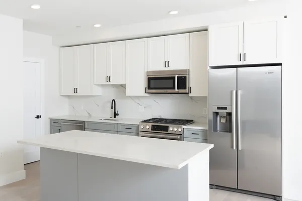 a kitchen with refrigerator a microwave a stove and cabinets