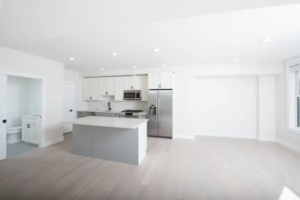 a view of a kitchen with refrigerator and white cabinets