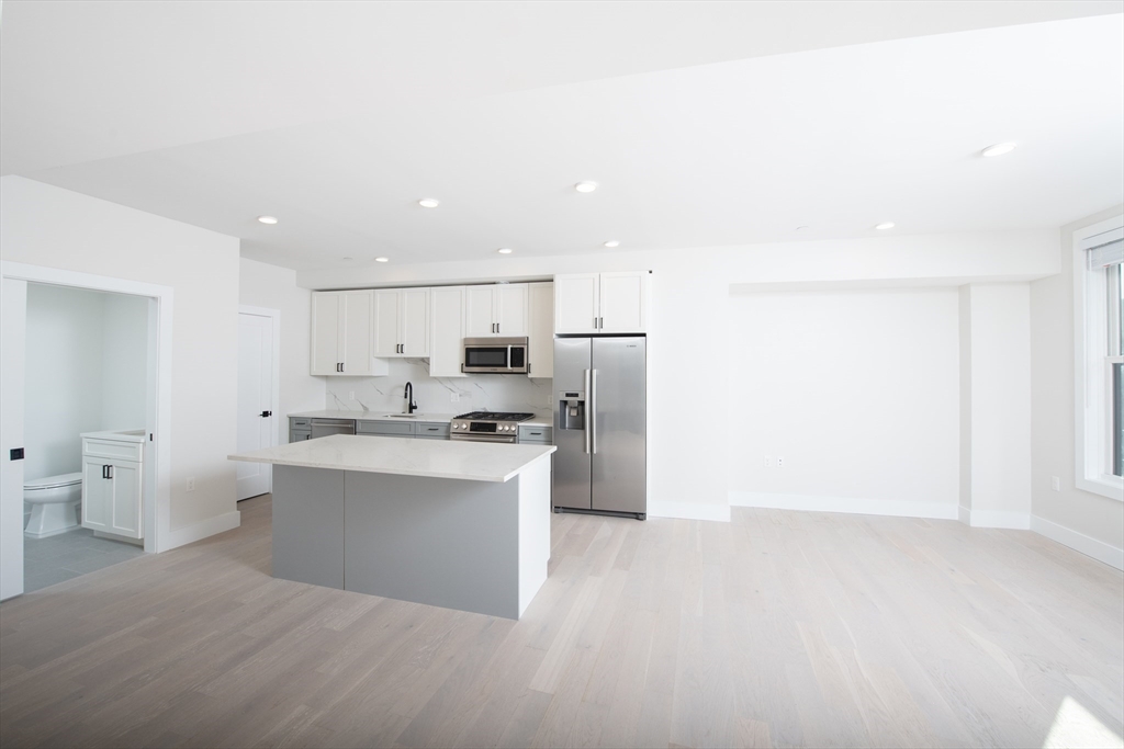 425 Border Street, Unit 307 Boston, MA 02128 - Photo 3 of 19 a view of a kitchen with refrigerator and white cabinets