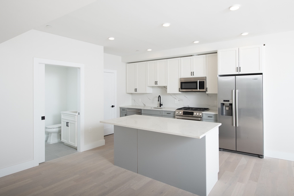 425 Border Street, Unit 307 Boston, MA 02128 - Photo 4 of 19 a kitchen with stainless steel appliances a refrigerator stove microwave and cabinets