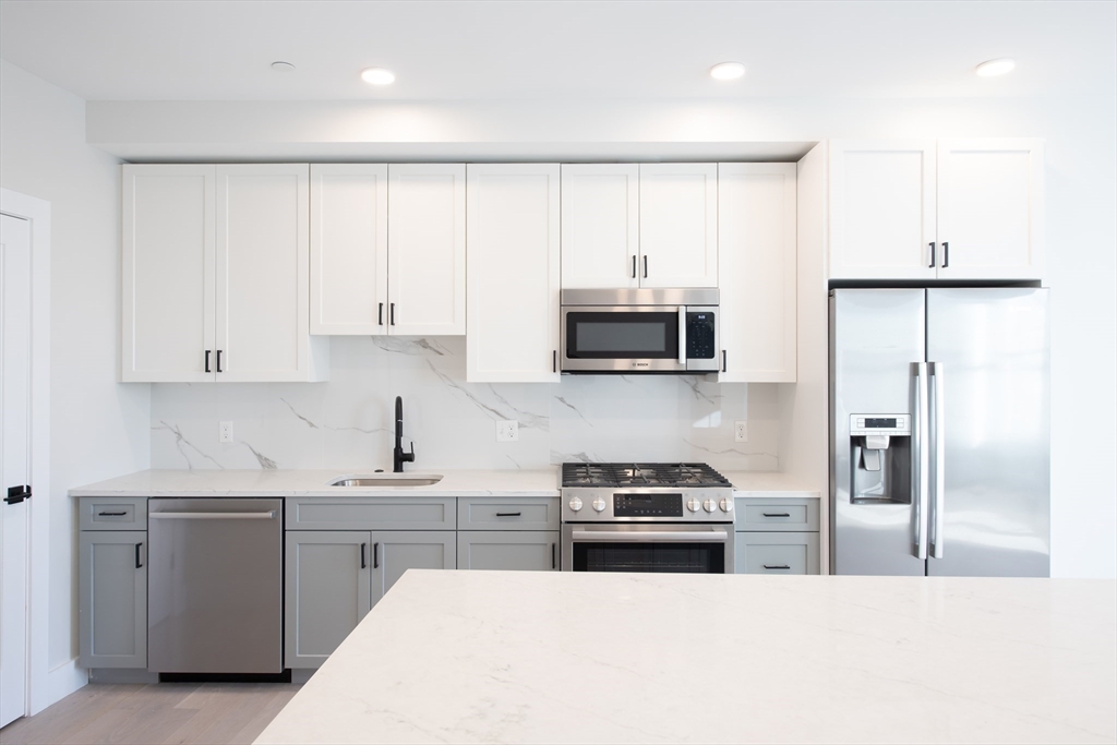 425 Border Street, Unit 307 Boston, MA 02128 - Photo 5 of 19 a kitchen with white cabinets and stainless steel appliances