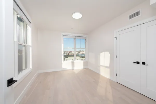 a view of an empty room with wooden floor and a window