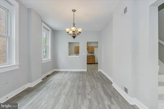 a view of empty room with wooden floor chandelier and window