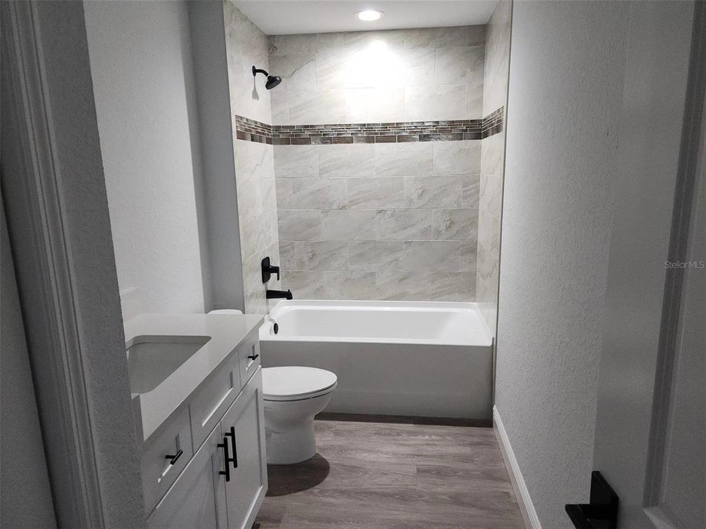 1111 Dagmar Avenue Spring Hill, FL 34606 - Photo 7 of 27 a bathroom with a granite countertop sink toilet and shower