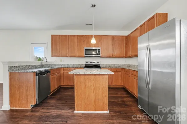 a kitchen with granite countertop wooden floors stainless steel appliances a sink and a window