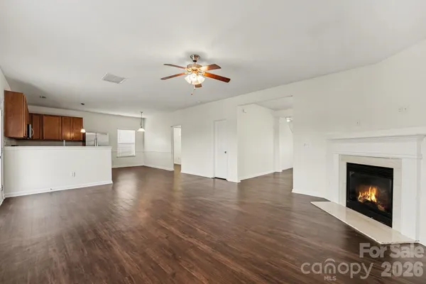 a view of a livingroom with fireplace a ceiling fan and wooden floor