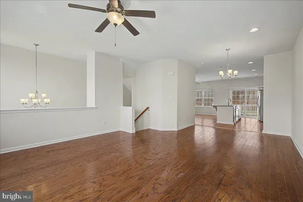 an empty room with ceiling fan and windows