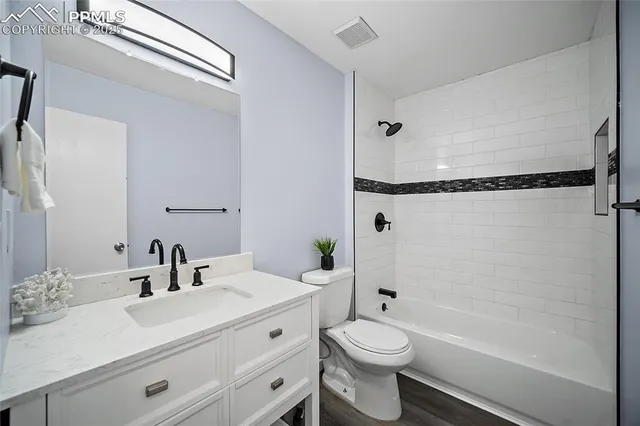a bathroom with a granite countertop sink a toilet and shower