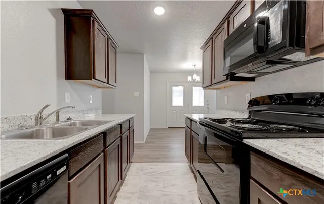 a kitchen with stainless steel appliances granite countertop a stove a sink and a microwave