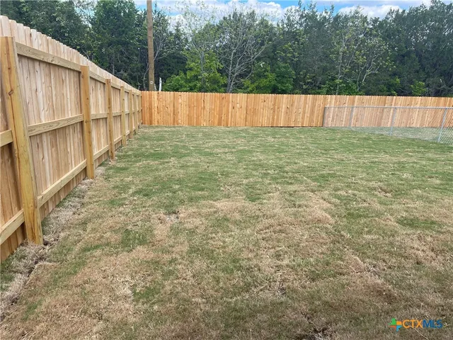 a view of a backyard with wooden fence