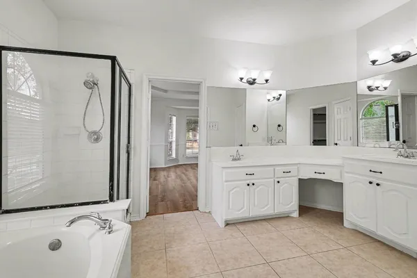 a spacious bathroom with a double vanity sink a mirror a bathtub and shower