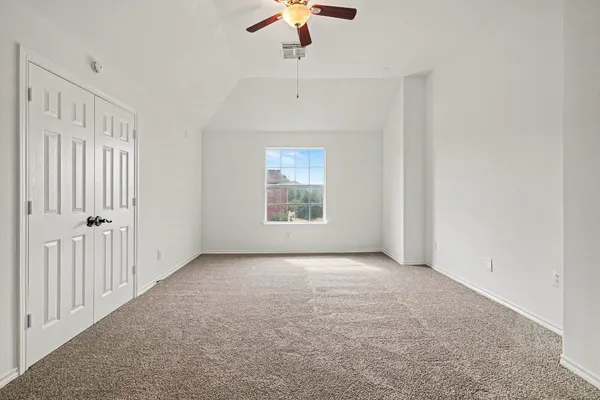 an empty room with a chandelier fan and windows