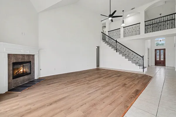 a view of an empty room with wooden floor a fireplace