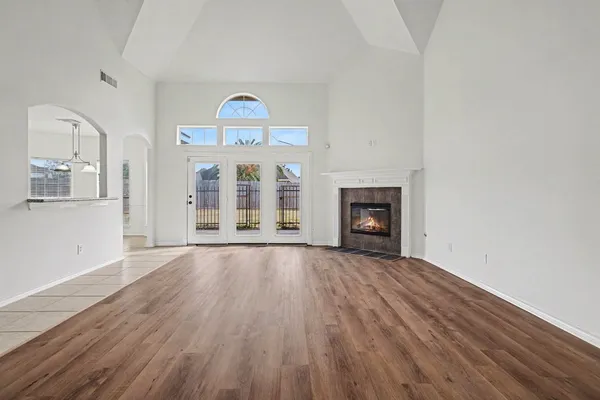 an empty room with wooden floor fireplace and windows